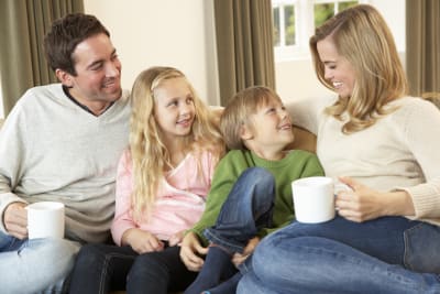Familj med två vuxna och två barn ungås i soffan.
