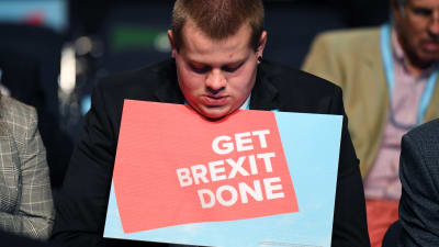 En ung man ses hålla i en skylt med orden "Get brexit done" (fixa brexit) .