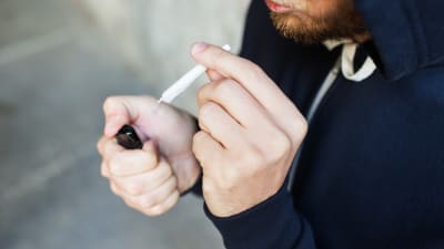 Närbild på en anonym man som håller på att tända en joint.