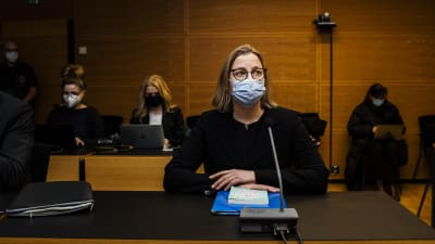 Tytti Yli-Viikari sitter vid ett bord i tingsrätten. Hon har munskydd på sig.