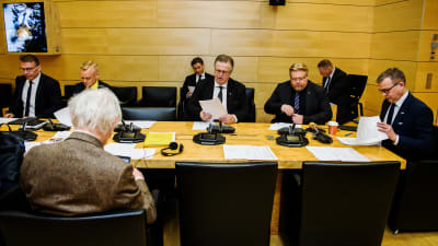 Försvarsutskottets medlemmar sitter runt ett bord under ledning av Petteri Orpo. 