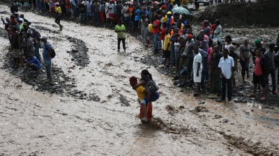Människor försöker ta sig över floden La Digue i sydvästra Haiti.