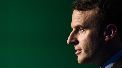 Emmanuel Macron i profil mot svart bakgrund.