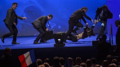 En aktivist bärs ut från scenen av Le Pens säkerhetsvakter.