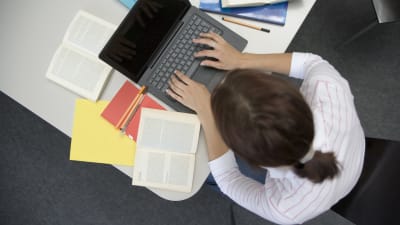En kvinna studerar och skriver på datorn.