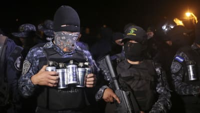Poliser i Honduras står maskerade vid en polisstation.