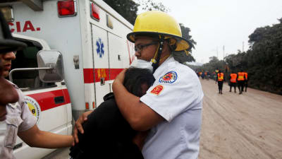 En brandman kramar Eufemia Garcia som förlorade sin familj i Eldvulkanens utbrott.