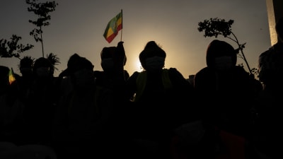 Etiopiens flagga vajar och i förgrunden svarta siluetter av människor i militär klädsel