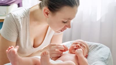 Ung mamma som talar med sitt nyfödda barn.