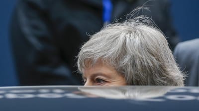 Premiärminister Theresa May delvis skymd bakom en bil.