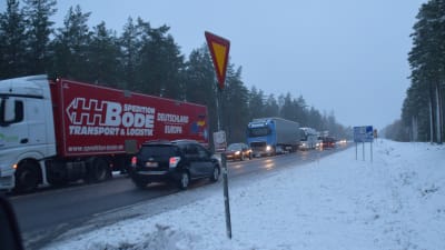 Fordon står i en kö på en snöig väg.