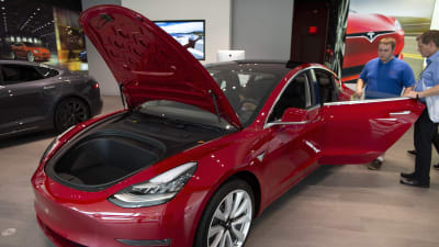 En potentiell köpare bekantar sig med en Tesla Model 3 hos en bilhandlare i Boston den 7 augusti 2018.