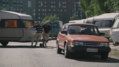 Kasper Strömman och Pehr-Olof Eklund kopplar en husvagn bakom en röd Saab.