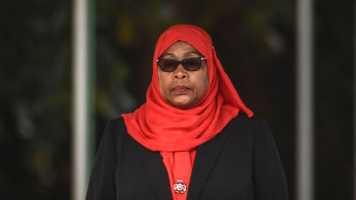 Samia Suluhu Hassan, svartklädd med klarröd sjal och mörka solglasögon.