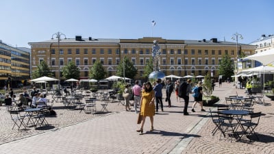Personer på kaserntorget i Helsingfors och uteservering med koronasäkra avstånd. 
