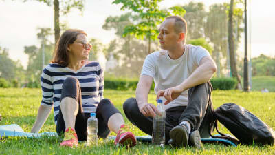 Man och kvinna sitter på gräsmatta och ser på varandra