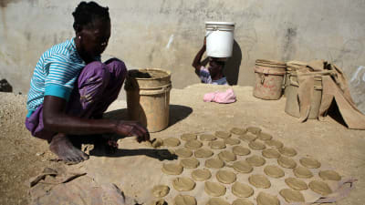 En kvinna i Cité Soleil bakar kakor med lera, olja och salt för att dämpa hungern.