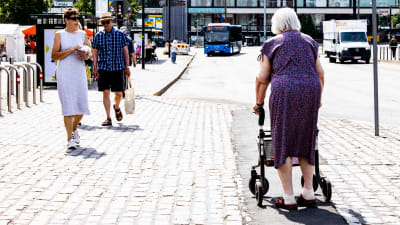 En äldre person rör sig över ett torg en varm sommardag. 