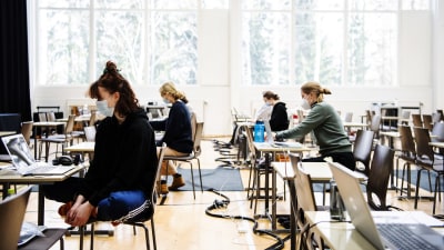 Studentskrivningar i ett gymnasium i Helsingfors i mars 2021. De studerande bär munskydd.