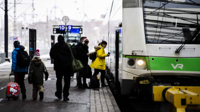 Tågresenärer stiger på ett grönt Intercitytåg på Helsingfors tågstation. 