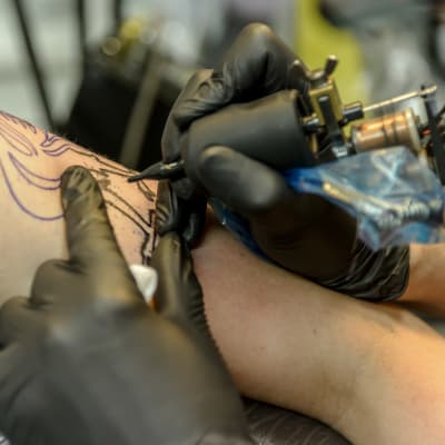 En person tatueras med en tatueringsmaskin.