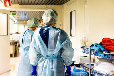 Sjukskötare i skyddsmundering står i en korridor och förbereder sig på att föra coronapatienter till isolering.