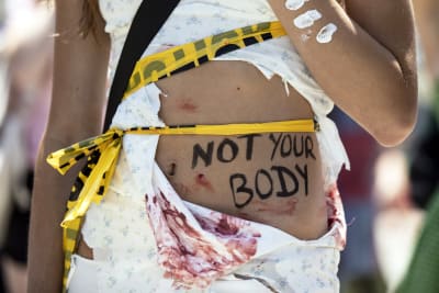 Mielenosoittajan vatsassa kirjoitus: "Not Your Body".