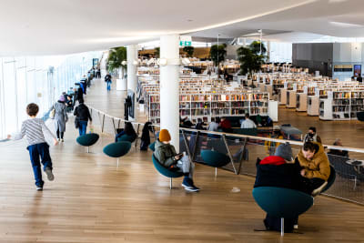 Biblioteket Odes tredje våning med fåtöljer och tiotals rader av vita bokhyllor med en massa böcker i.