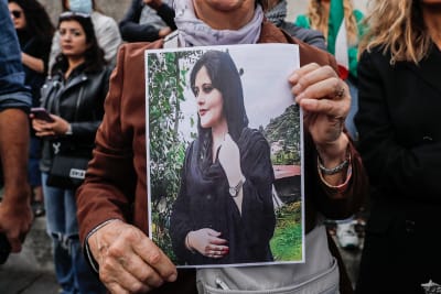 En av demonstranterna i Paris bar på ett porträtt av Mahsa Amini. 