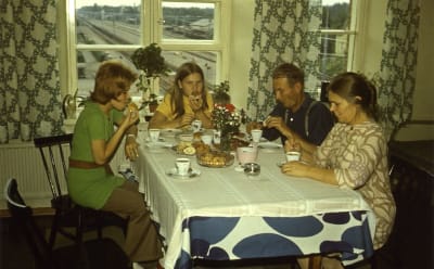 Familj som fikar, på kläder och inredning ser man att det är 1970-talet.