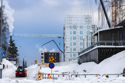 Bygge av nytt höghus, mycket snö på marken. 