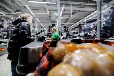 En person som betalar inköp vid en kassa i en mataffär.