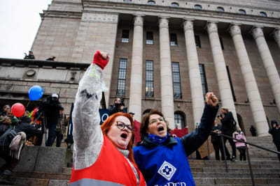 Tehys och Supers demonstranter höjer nävarna framför riksdagshuset.