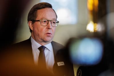 Näringsminister Mika Lintilä, en man i övre medelåldern med grånande hår och glasögon som bär kostym blir intervjuad framför en tv-kamera.