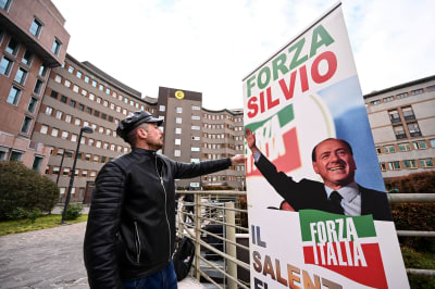 En man sätter upp en banderoll där det står "Forza Silvio!" framför sjukhuset San Raffaele i Milano där Italiens tidigare premiärminister, Silvio Berlusconi, vårdas