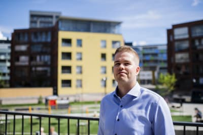 Juho Keskinen med moderna bostadshus och innergård i bakgrunden.