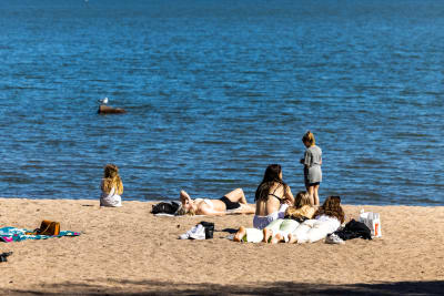 Sex personer på en solig strand med havet i bakgrunden.