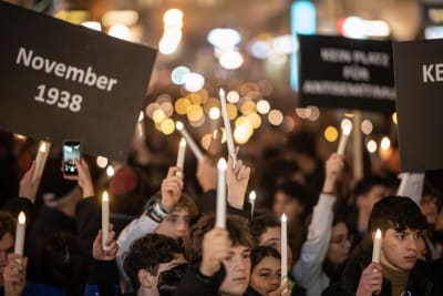 Personer går i demonstrationståg och håller i artificiella ljus.