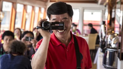 kiinalaisia turisteja lounaalla Finlandia Princessalla, kiinalaismies kuvaa handycam videokameralla
