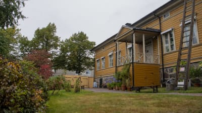 Ett gammalt gult trähus med omkringliggande trädgård.
