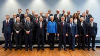 Ett gruppfoto med 24 män i kostym och två kvinnor. Mitt i den främsta raden står Christine Lagarde i knallblå jacka och mörka byxor.