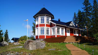 En röd fritidsbostad omringad av skog.