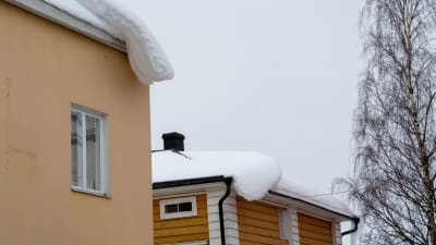 snö hänger ner från två tak.