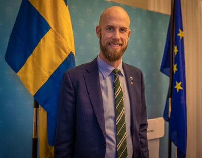 Carl-Oskar Bohlin står vid Sveriges och EU:s flagga.