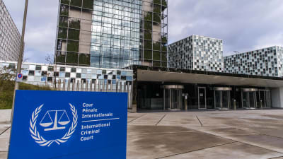 Internationella brottmålsdomstolens byggnad i Haag har en fasad i glas och stål. I förgrunden syns en skylt som identifierar byggnaden på franska och engelska.