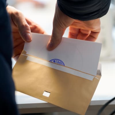 En röstsedel läggs i ett kuvert.