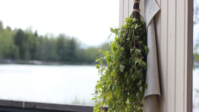 Bastukvast och handduk hänger på en bastudörr vid havet
