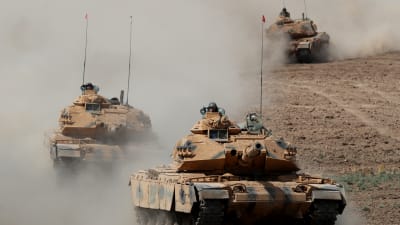 Tre turkiska stridsvagnar kör i ett löst led mot kameran. 