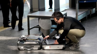 Passagerare på Atatürkflygplatsen i Istanbul placerar sin laptop i den incheckade bagaget.