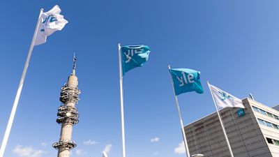 Kuvassa näkyy Pasilan tv-torni, sekä Ylen lippuja.